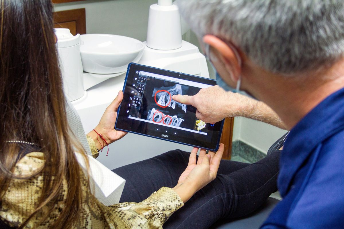 Dentista mostrando imágenes en una tableta a una paciente
